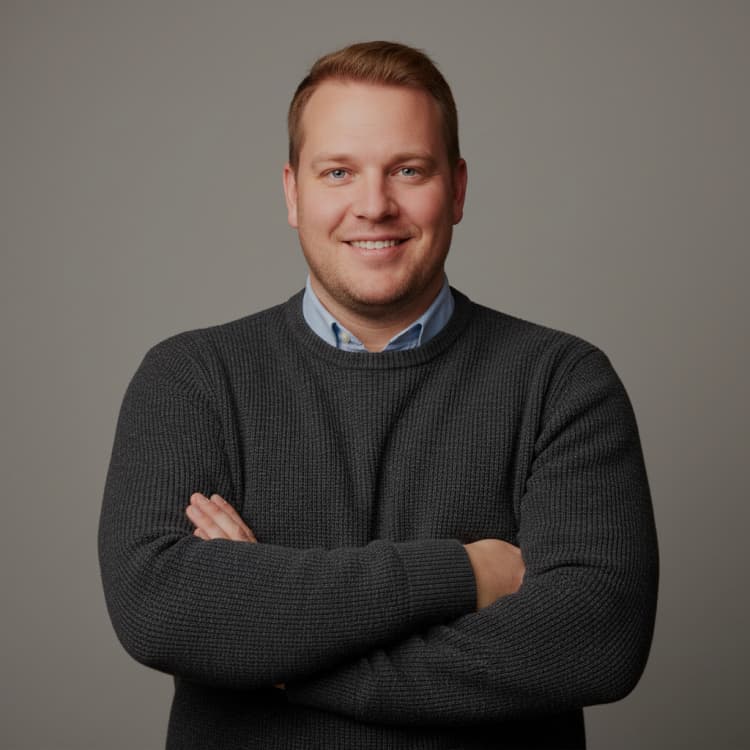 Smiling man in a charcoal knit sweater with his arms folded