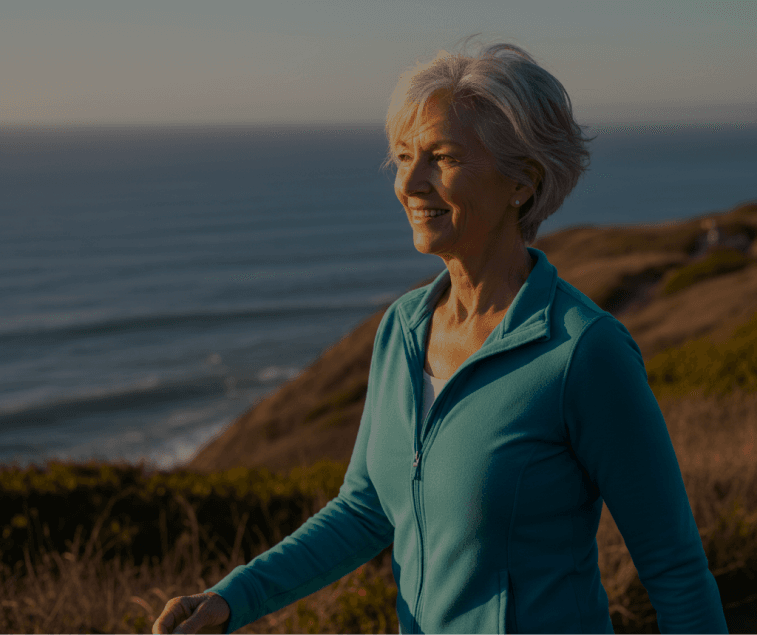Woman walking on a coastal path at sunset